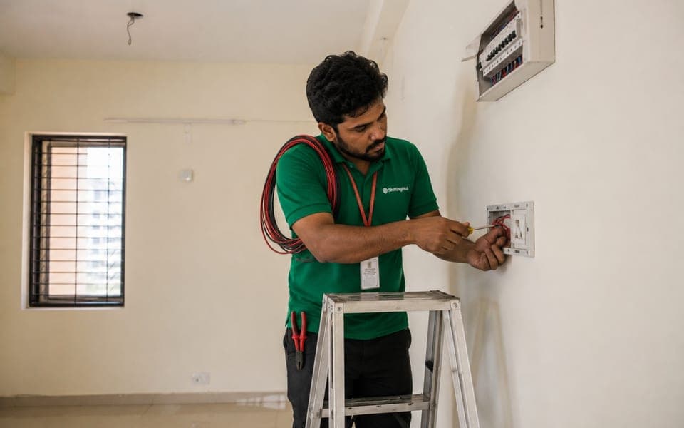 A ShiftingHub electrician on a ladder wiring a new power point into an open switch plate