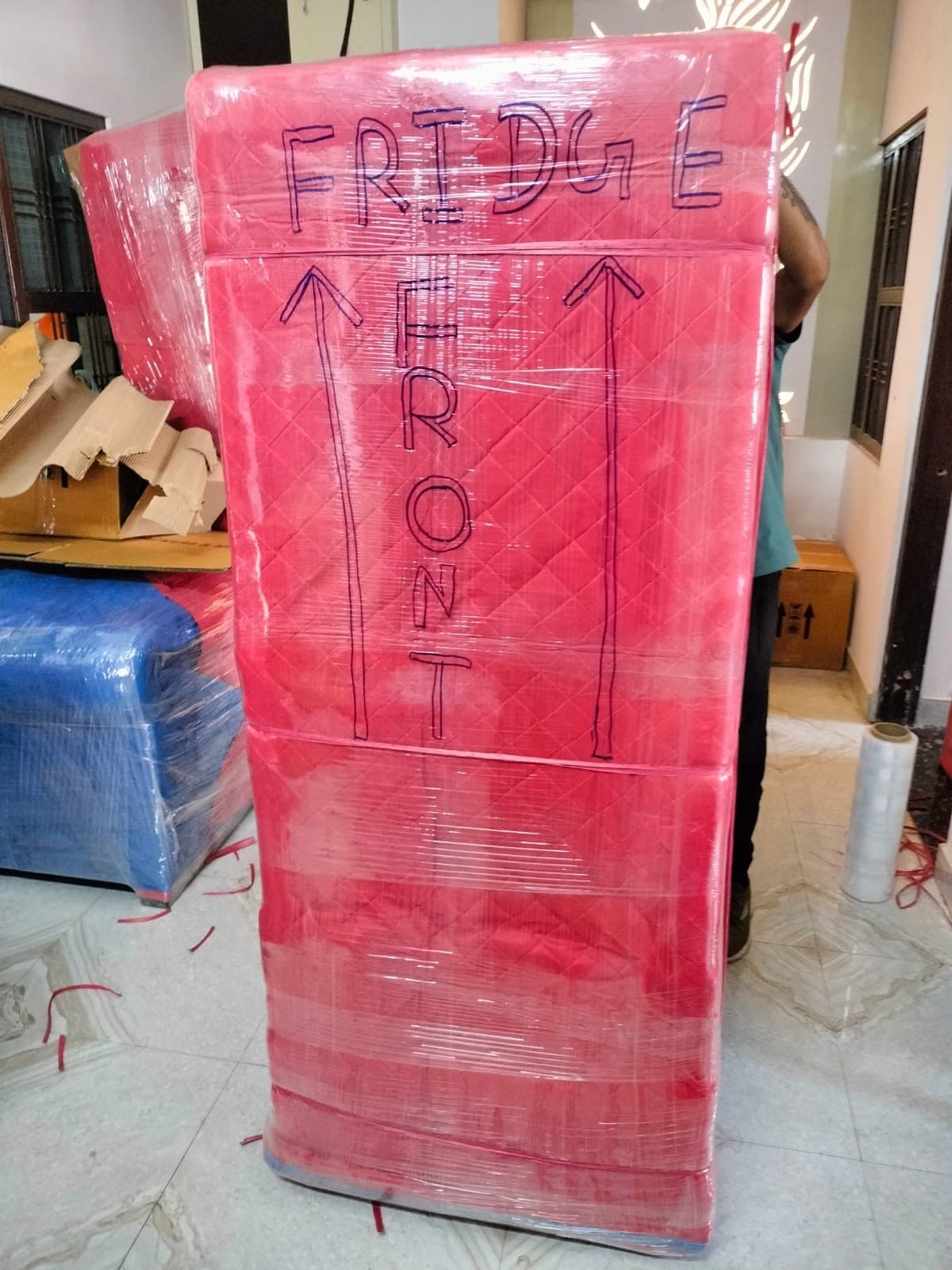 A fridge wrapped in quilted covers and marked front and this way up