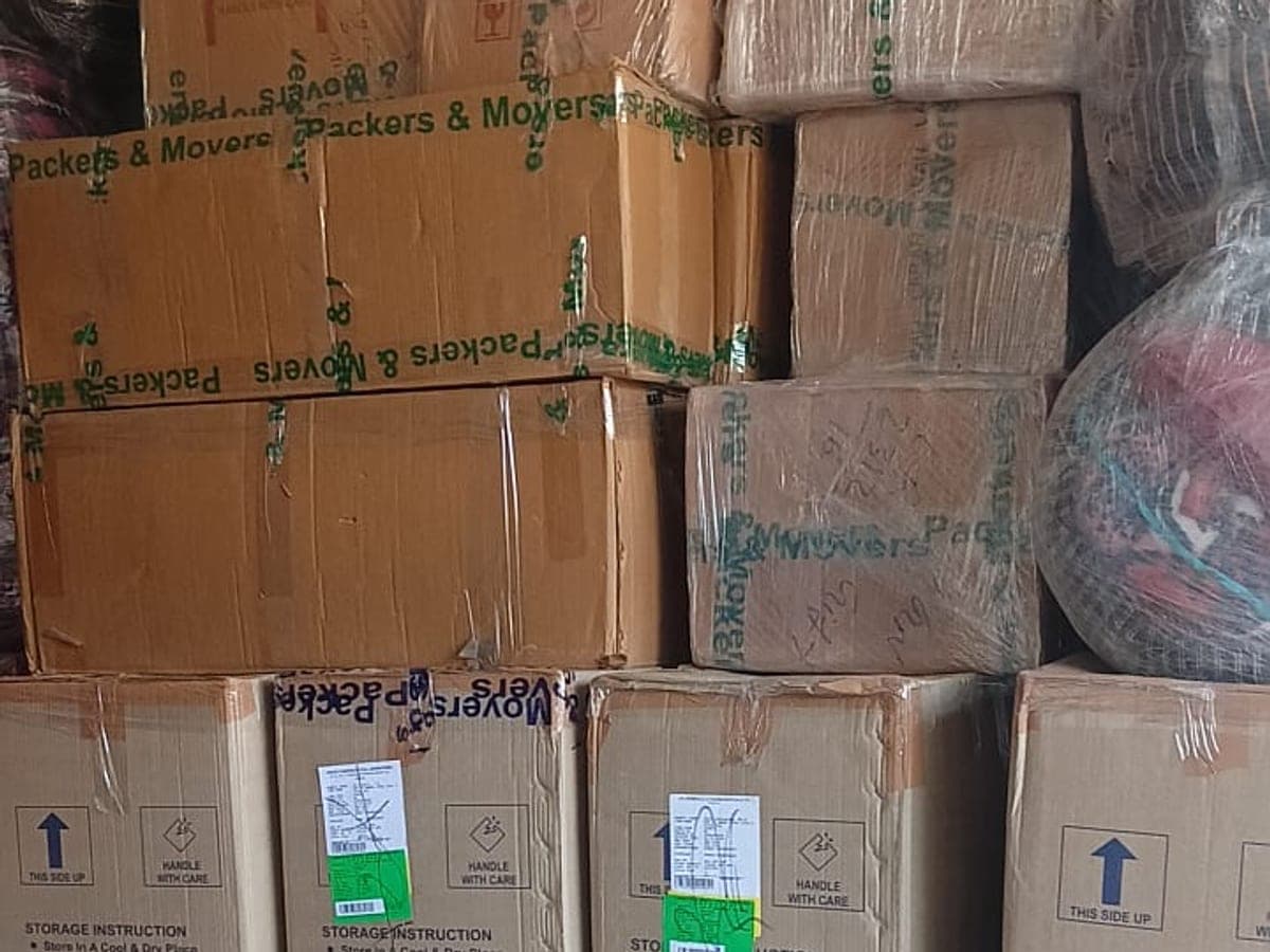 Stacked cardboard cartons sealed with branded tape and marked handle with care