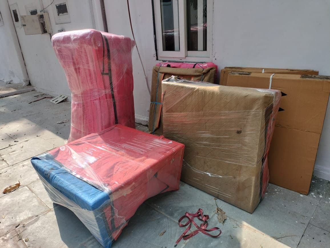 Chairs wrapped in red and blue film staged outdoors before loading