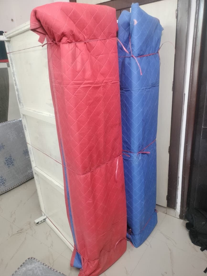 Furniture rolled and wrapped in quilted red and blue covers