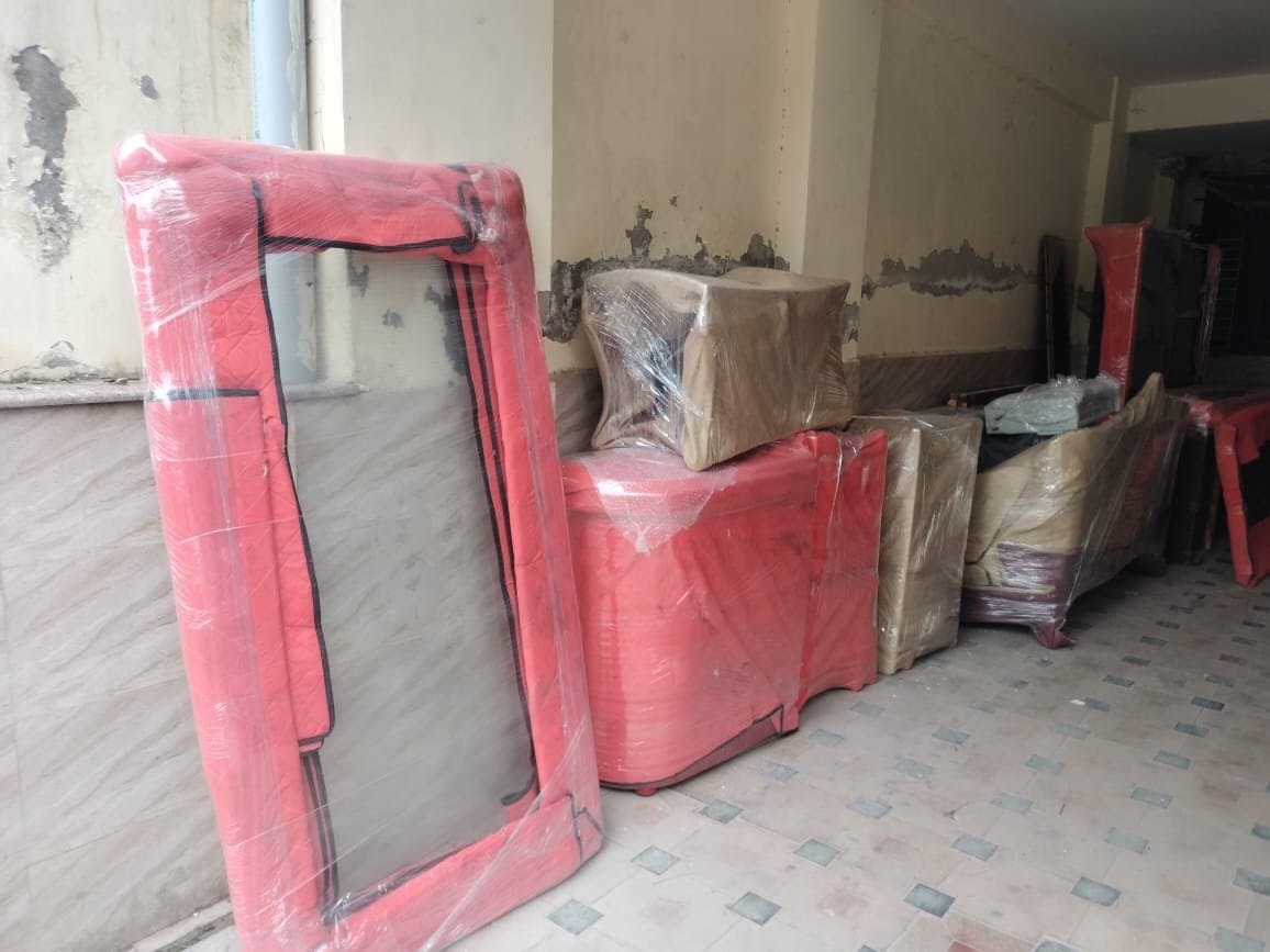 Mirror wrapped in a red quilted cover next to boxed furniture in a corridor