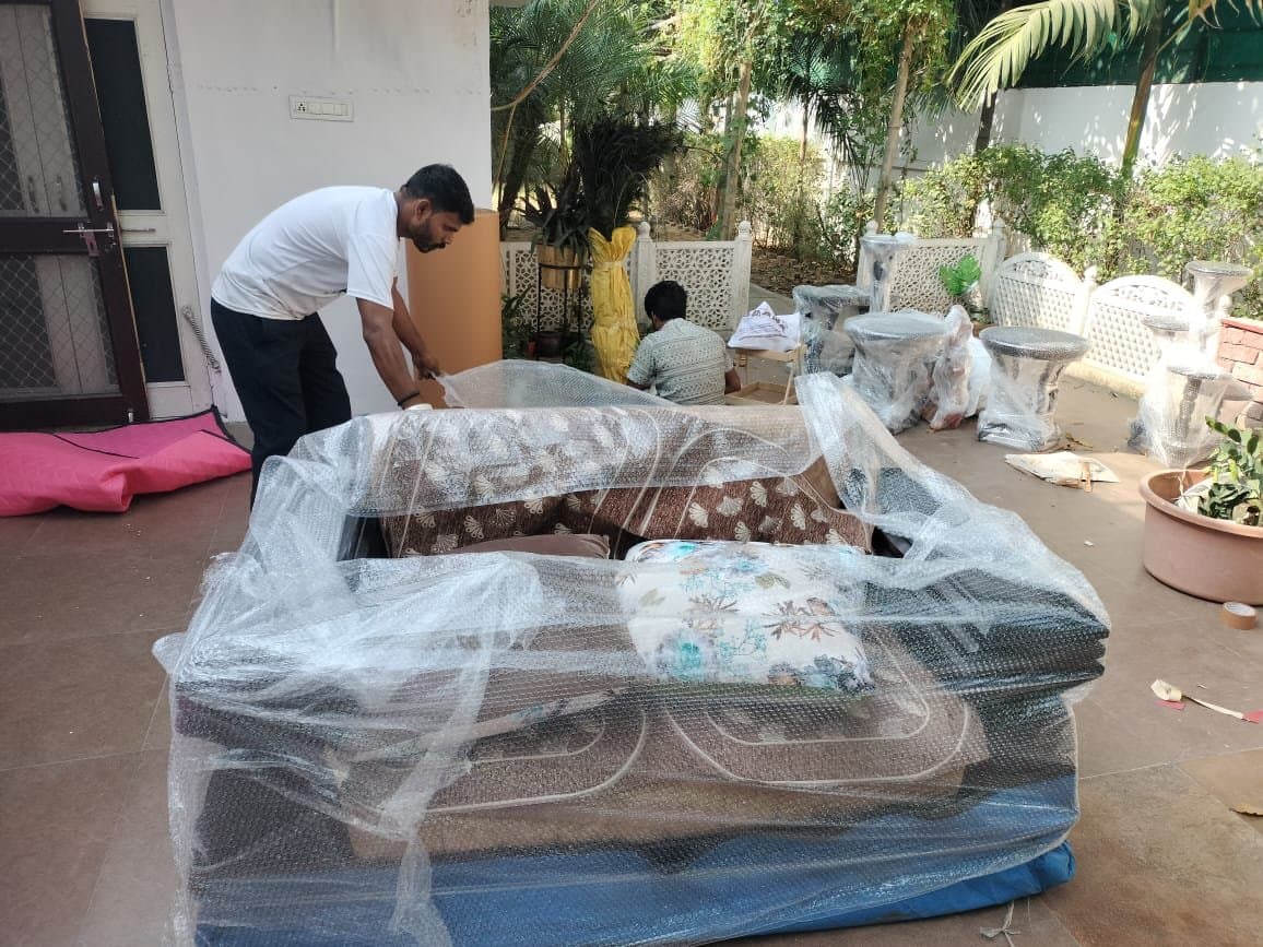 Team wrapping outdoor sofa furniture in bubble wrap on a patio