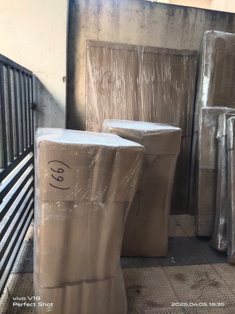 Door panels and furniture wrapped in stretch film on a balcony landing