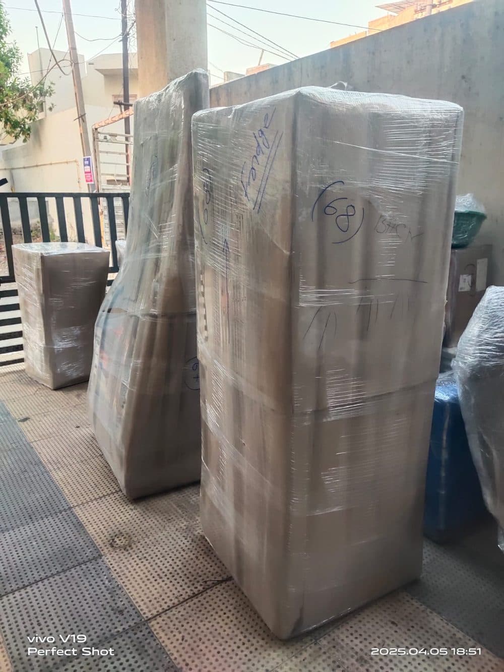 A refrigerator and wardrobe wrapped in protective film and labelled for transit