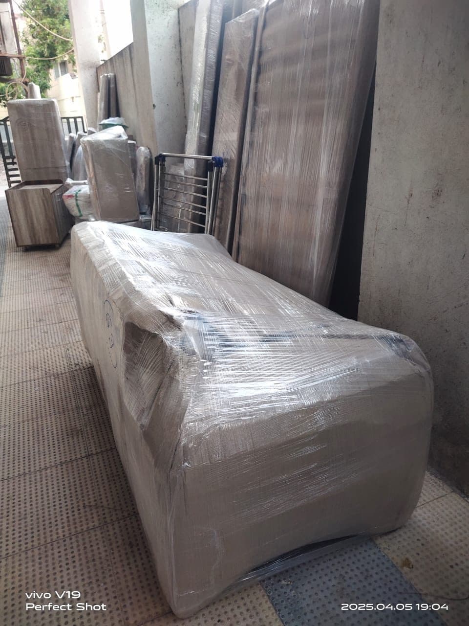 Sofa and packed furniture wrapped in stretch film and staged in a stairwell corridor before a move