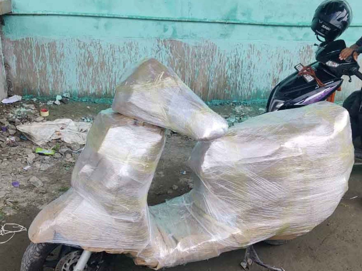 A scooter wrapped in stretch film and cardboard in a courtyard