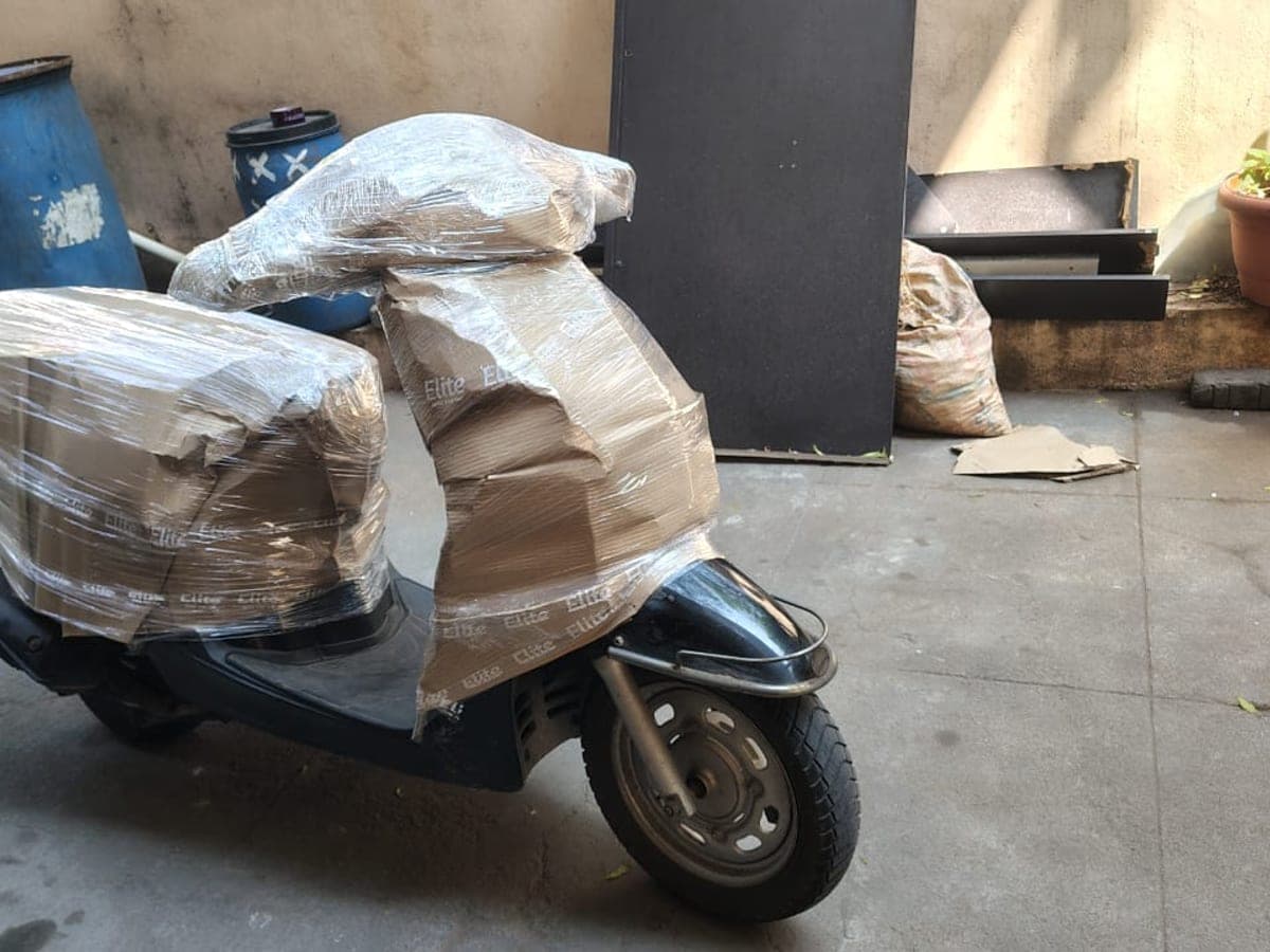 A scooter wrapped in stretch film and corrugated sheet in a courtyard