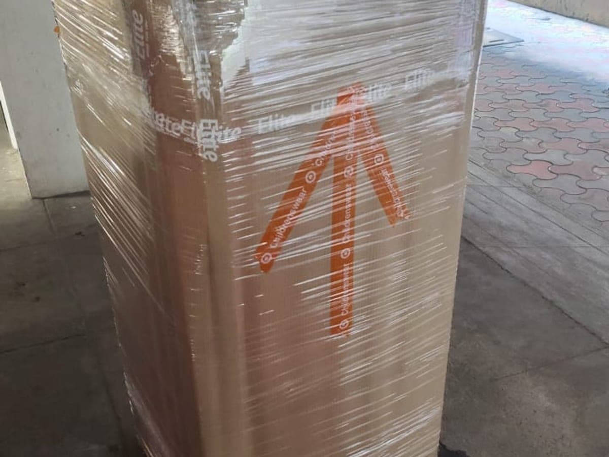 A tall carton wrapped in stretch film with an orange arrow taped on the side
