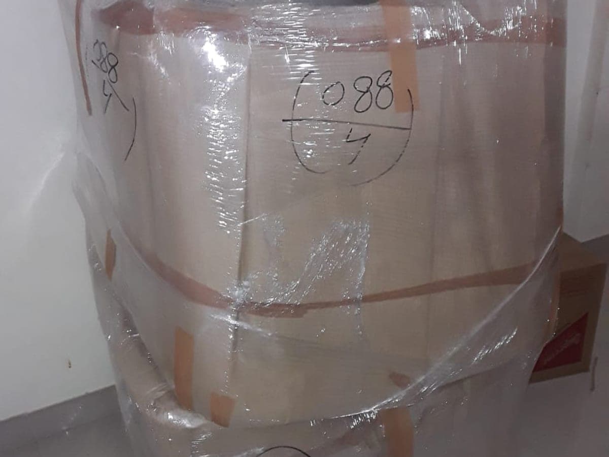 A wrapped item of furniture marked with a handwritten consignment number