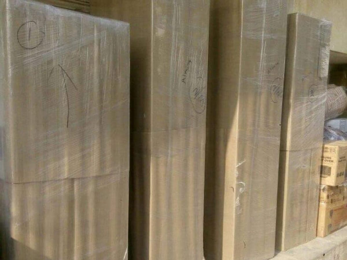 Wrapped mattresses and flat furniture panels staged upright against a wall before loading