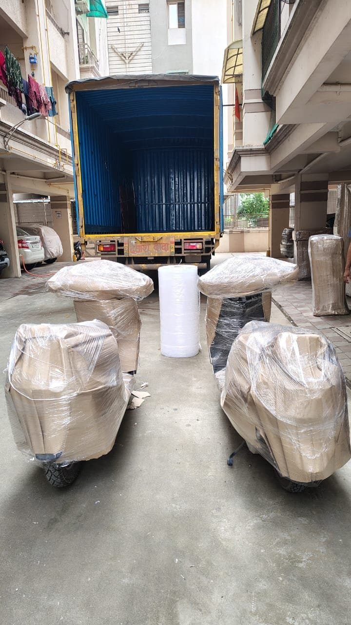 Four wrapped scooters staged in front of a container truck