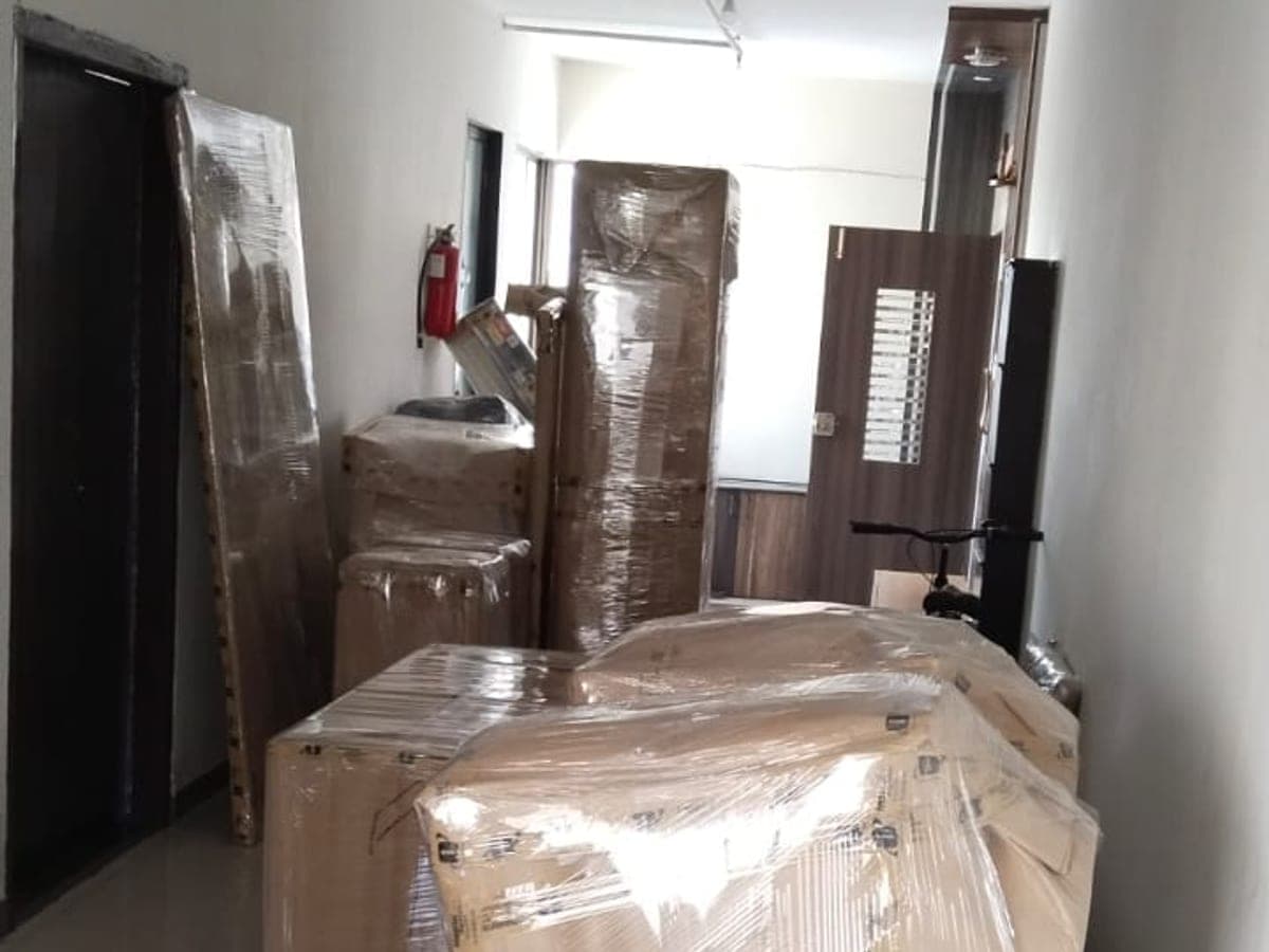 Wrapped furniture and boxed appliances staged in a building corridor