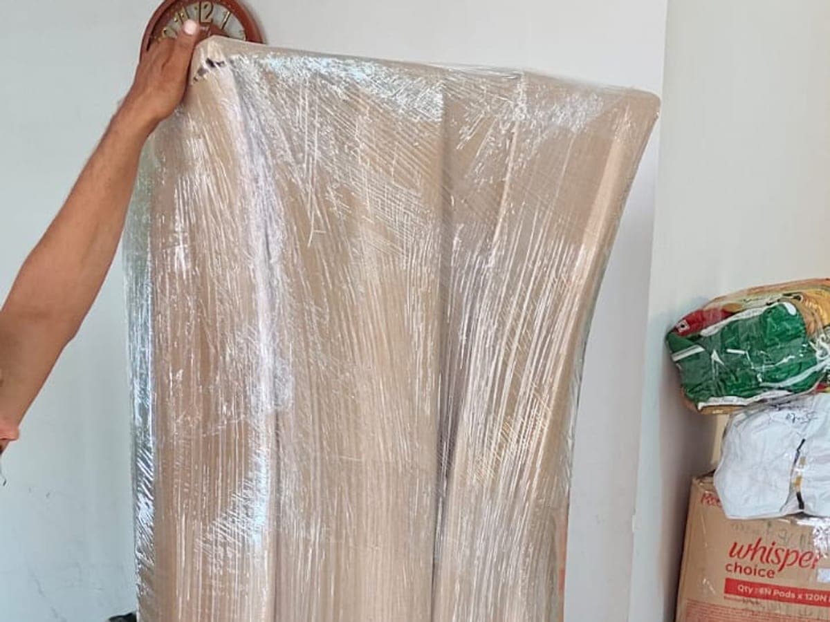An armchair wrapped in stretch film beside packed cartons in a customer's home