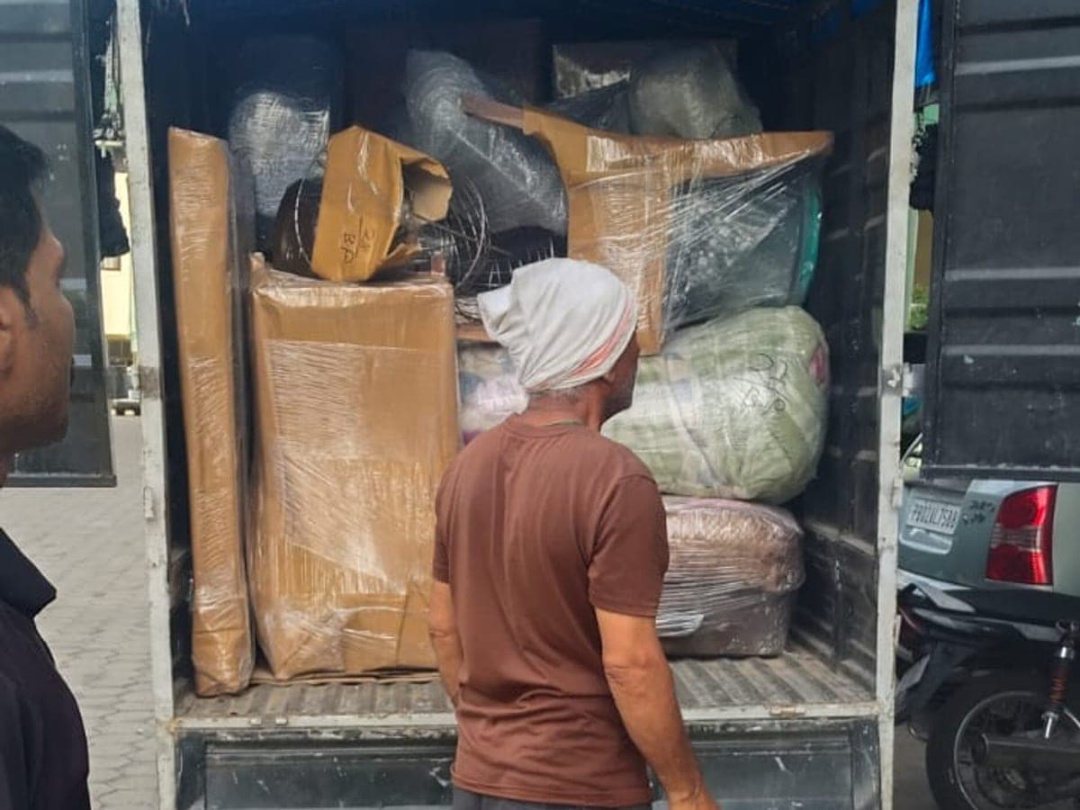 A tempo loaded with wrapped furniture, cartons and bagged goods, with a mover standing at the tailgate