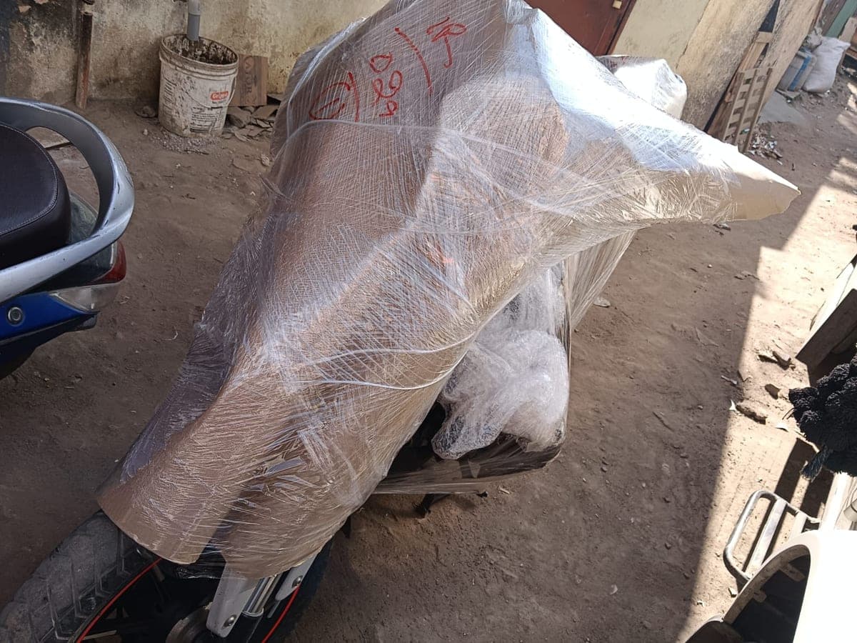 A motorcycle wrapped in stretch film and marked with a handwritten inventory number