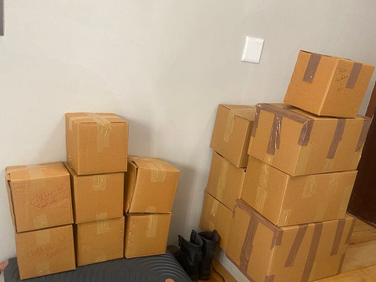 Stacked cardboard cartons labelled by room and content inside a home