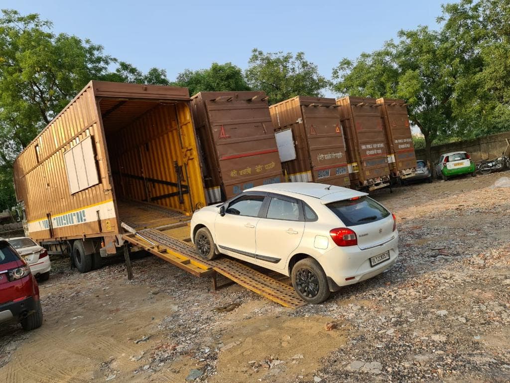 Car being driven onto an enclosed carrier at a transport yard