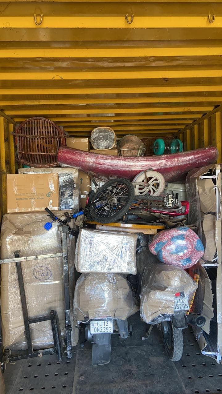 Container packed floor to roof with wrapped household goods and two-wheelers