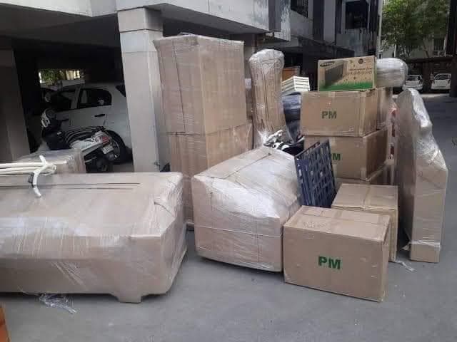 Wrapped furniture and labelled cartons staged outside a building