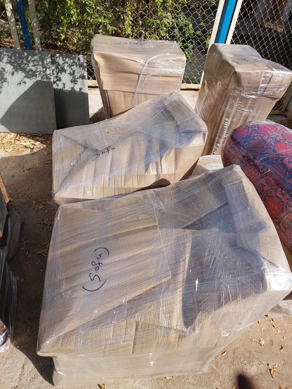 Sofa sections wrapped and labelled, staged outdoors before loading