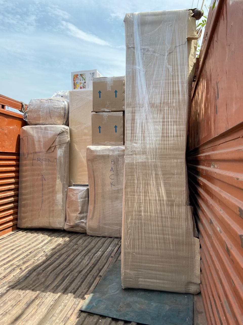 Wrapped cartons and furniture labelled front and back on a truck bed
