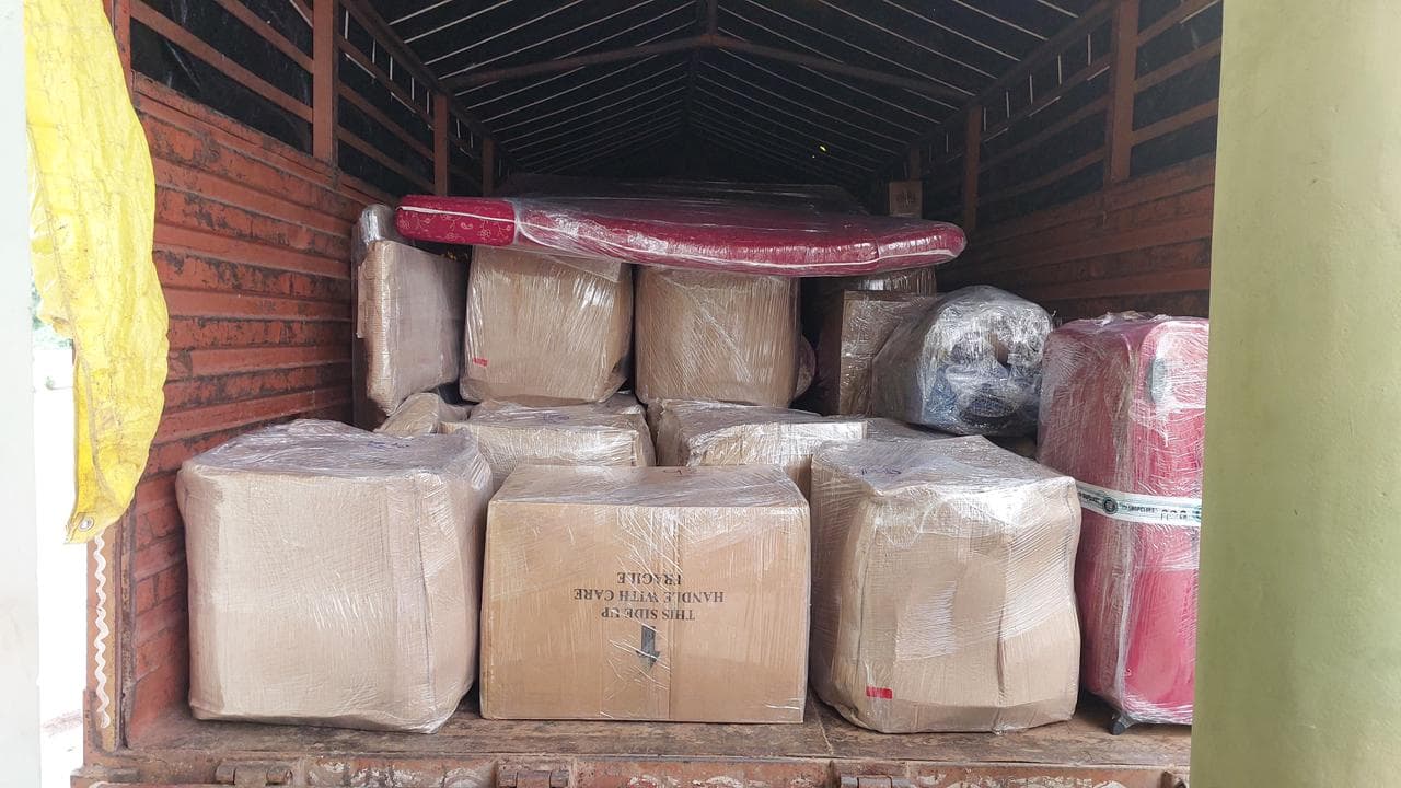 Truck loaded with stretch-wrapped cartons, suitcases and a mattress