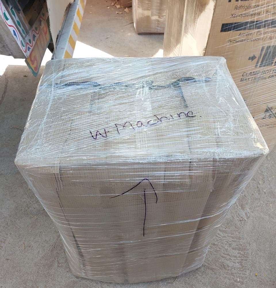 A washing machine packed in a carton and stretch film, marked this way up