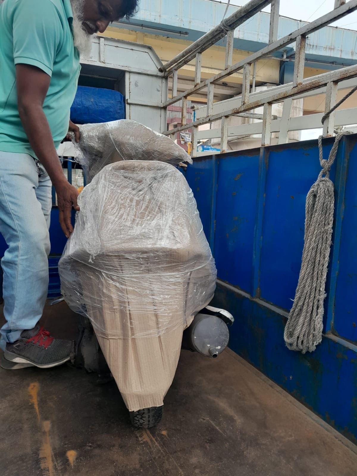 Mover wrapping a scooter in plastic sheeting inside a loaded truck