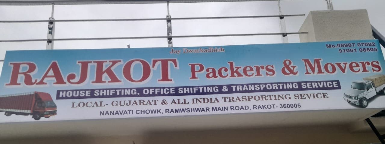 Rajkot Packers and Movers signboard above a shuttered storefront
