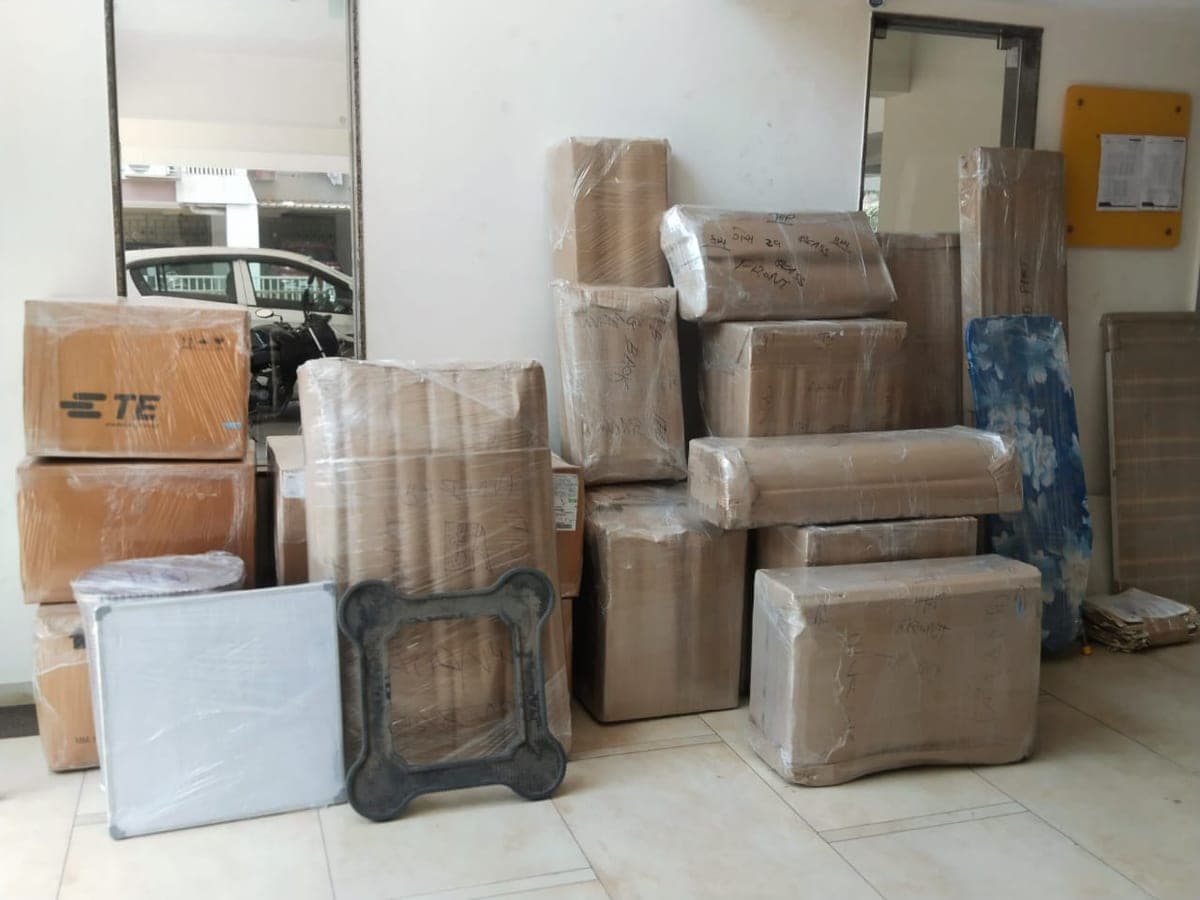 Packed cartons and a wrapped ironing board staged at an entrance