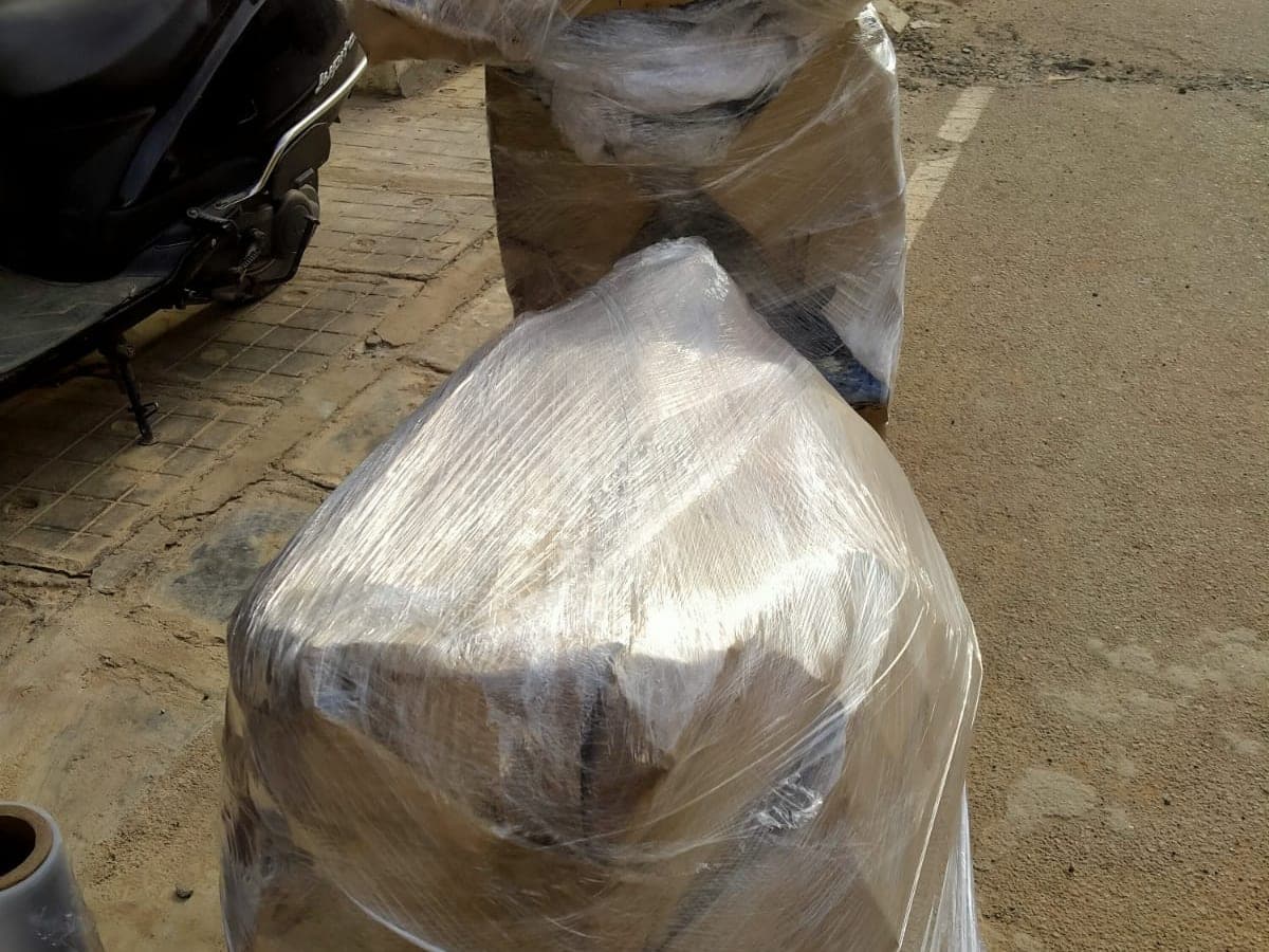 Wrapped furniture and cartons staged outdoors before loading, beside a parked scooter