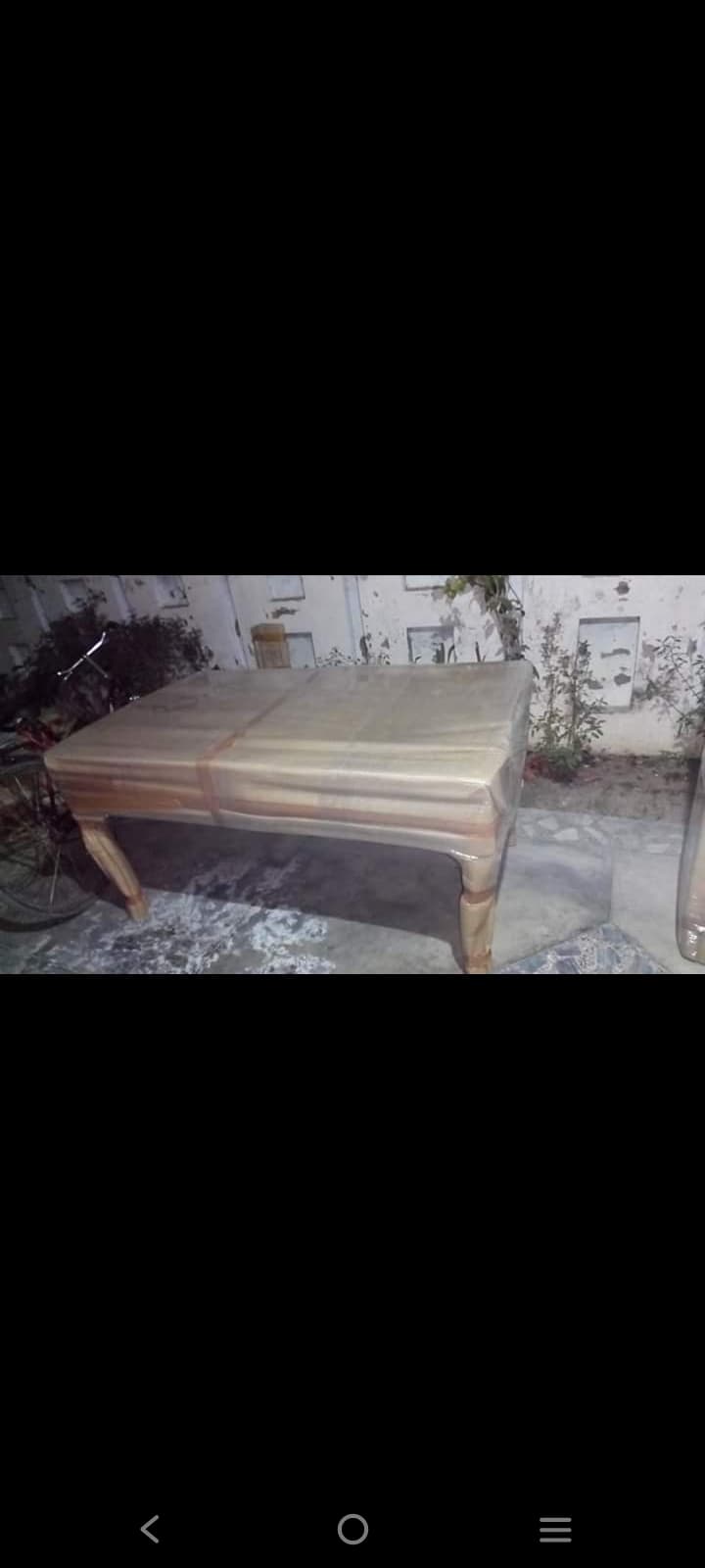 Wooden dining table wrapped in protective sheets before transit