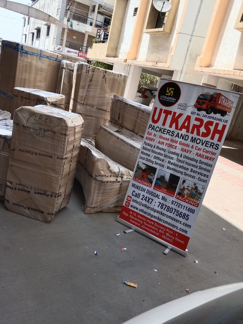 Utkarsh Packers and Movers signage beside packed household goods